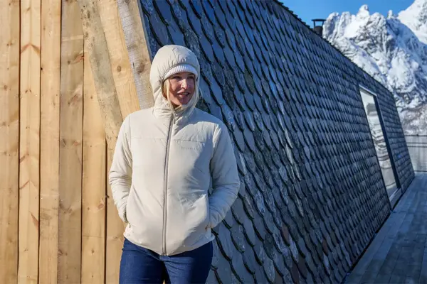 Dame i boblejakke med hvitkledde fjell i bakgrunn
