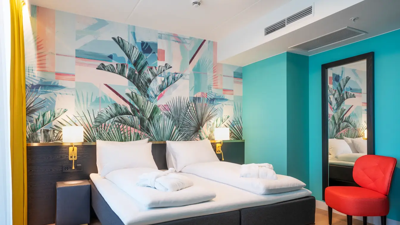Dobbeltseng med tapet med jungelblader på suite på Thon Hotel Storo i Oslo