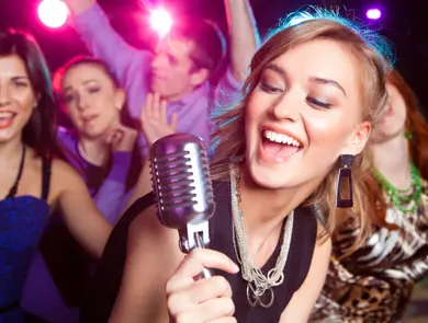 Young girl singing into  microphone at  party
