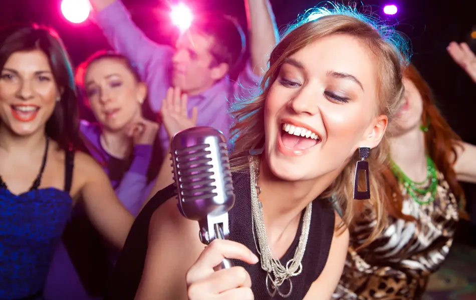 Young girl singing into  microphone at  party