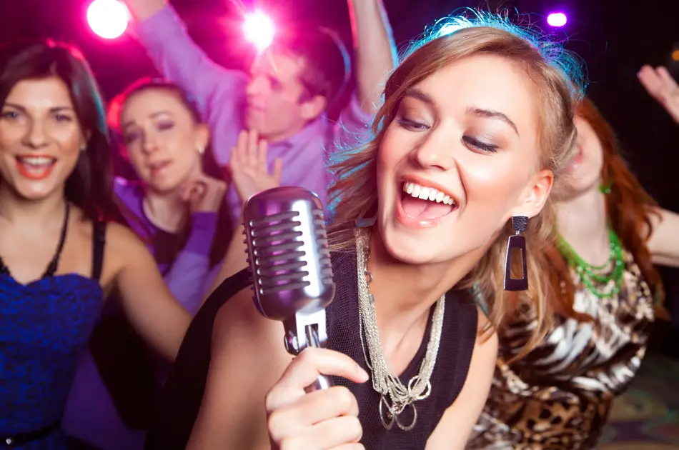 Young girl singing into  microphone at  party