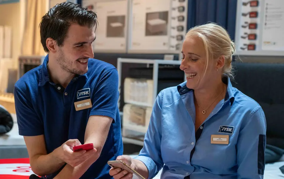 to ansatte på jysk som ser på en mobil