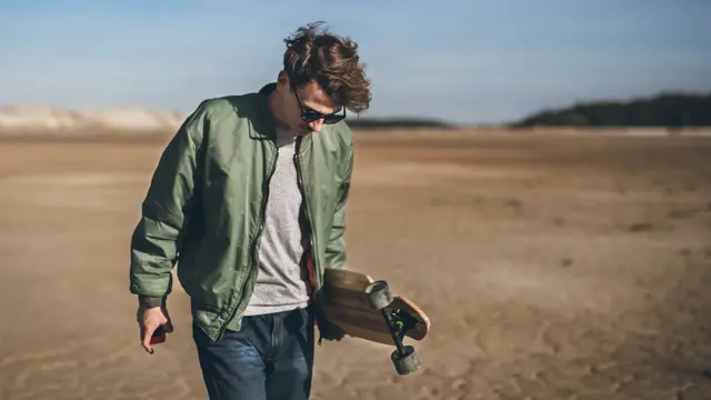 Young rebelious skater with his board, walking alone