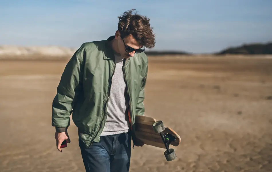 Young rebelious skater with his board, walking alone