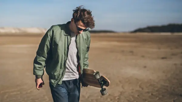 Young rebelious skater with his board, walking alone