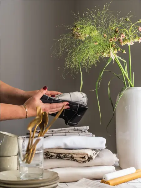 Dame som holder kjøkkenkluter og en vase med grønn blomster