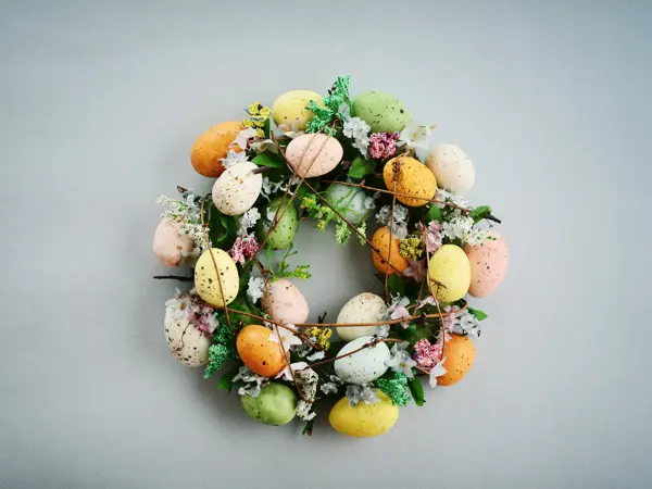 Decoration from easter eggs in shape of circle on painted wooden background