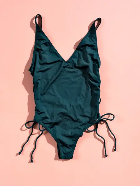 Grønn badedrakt med stropper på rosa bakgrunn