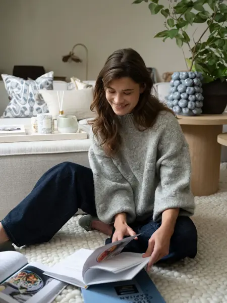 Dame som sitter på gulvet og leser i en bok