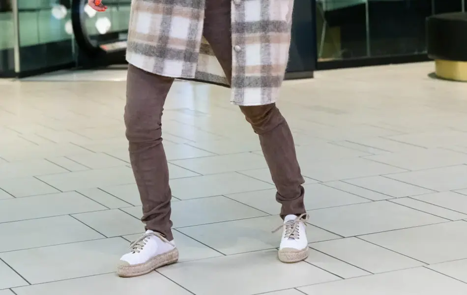 Ung kvinne som poserer i rutete skjortejakke og brune bukser