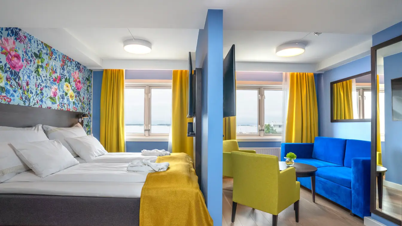 Dobbeltseng med morgenkåper på og avskilt sittegruppe med stoler og sofa i superior rom på Thon Hotel Moldefjord