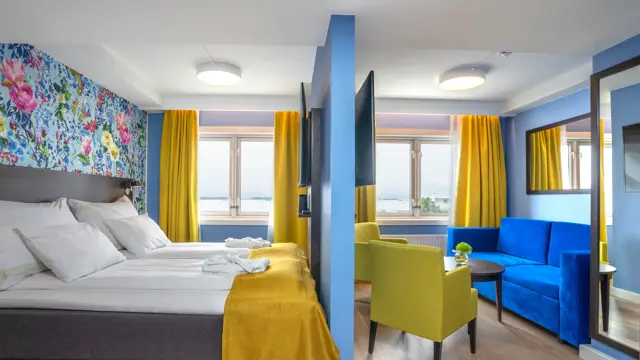 Dobbeltseng med morgenkåper på og avskilt sittegruppe med stoler og sofa i superior rom på Thon Hotel Moldefjord