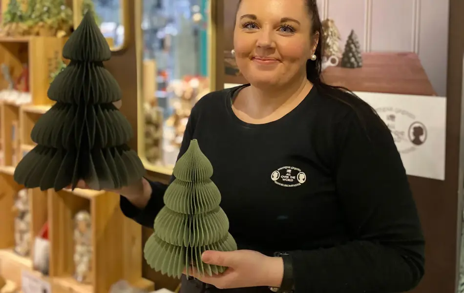 ansatt hos søstrene grene viser julepynten to grønne papirtrær