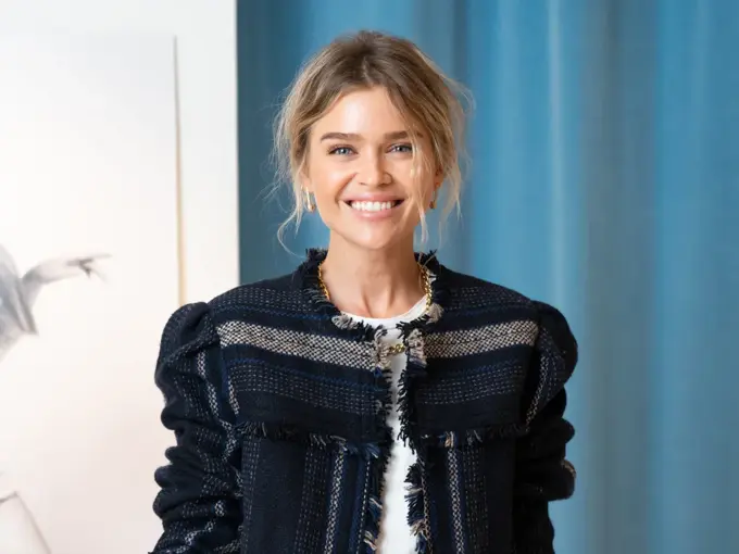 Dame i jakke foran blå vegg