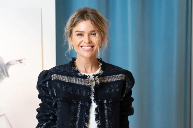 Dame i jakke foran blå vegg