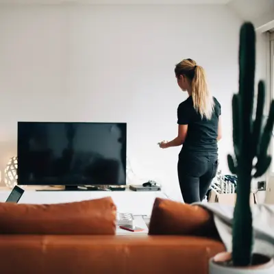 En dame bruker pc og en dame ser på tv 