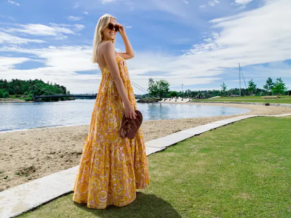 Jente med lyst hår og gul kjole på en strand
