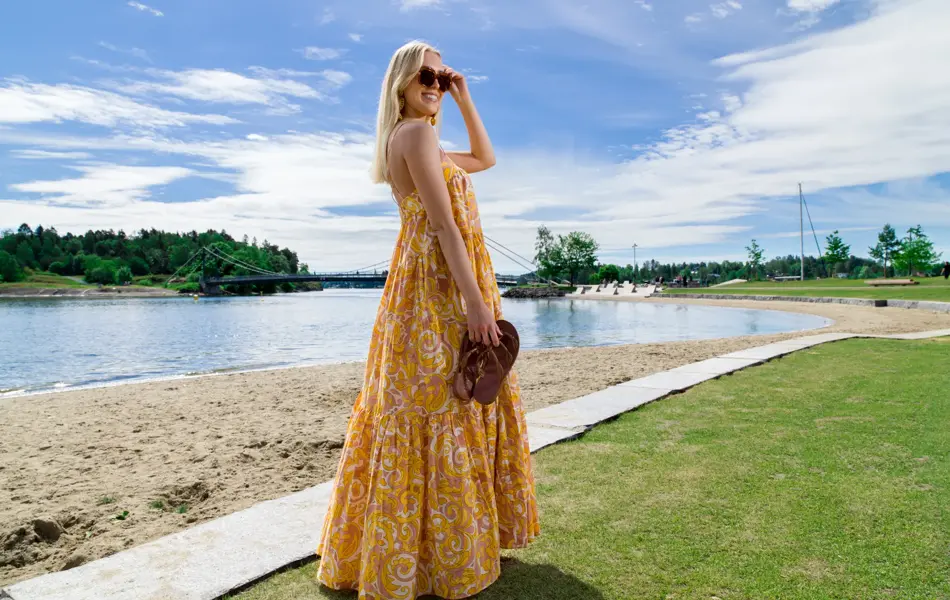 Jente med lyst hår og gul kjole på en strand