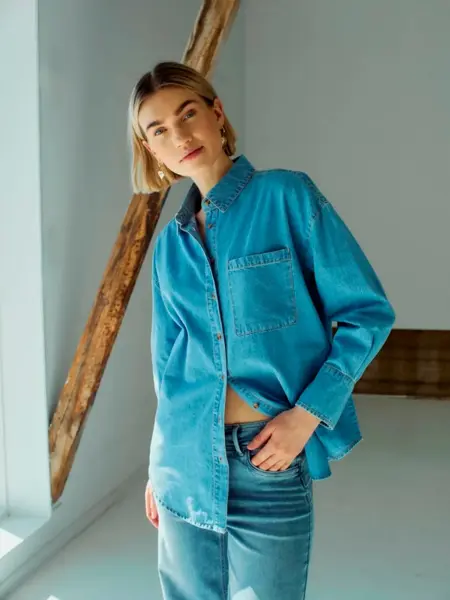 Damemodell i jeansskjorte og jeans.
