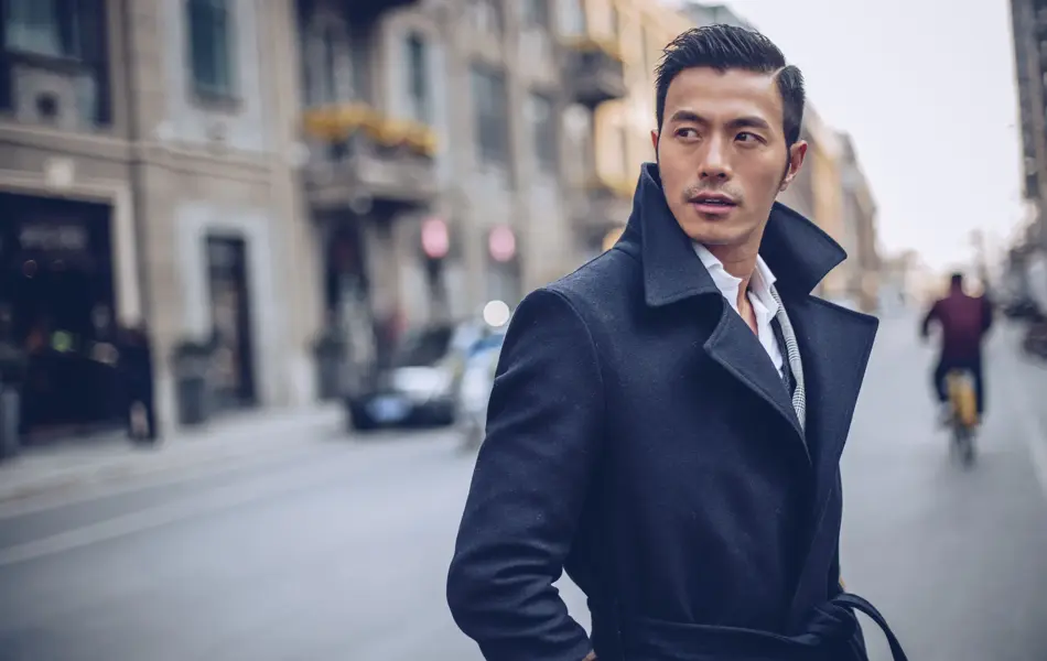 Mørkhåret mann i by iført svart ullfrakk.