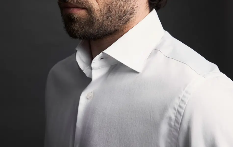 Nærbilde av skuldrene til en mann i hvit skjorte