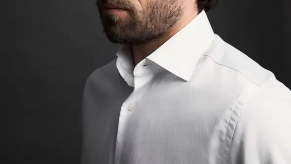 Nærbilde av skuldrene til en mann i hvit skjorte