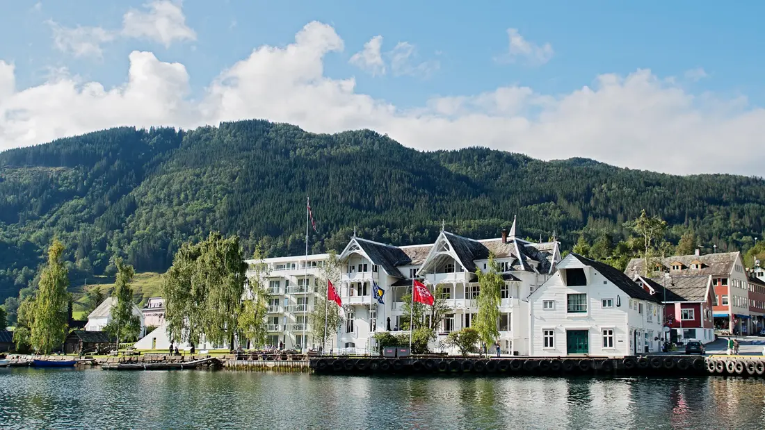 Fasade av Thon Hotel Sandven på sommeren med vann i forgrunnen 