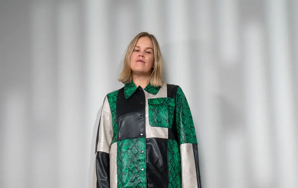 Damemodell i kort skjørt, sorte pumps og fargerik skjorte