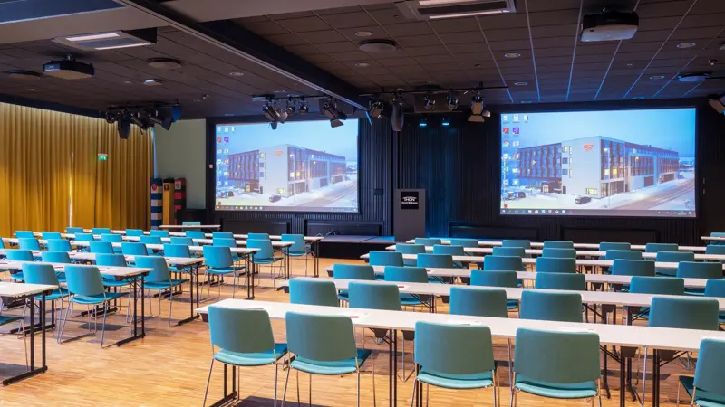 Turkise stoler og hvite bord i klasserom oppsett i konferanserom på Thon Hotel Kirkenes