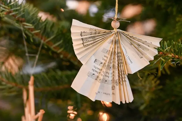 Brettet papirengel med noter hengende på juletre