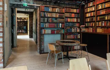 Bord og stoler i et hjørne med bokhyller med mange bøker på Kulturhuset i Oslo