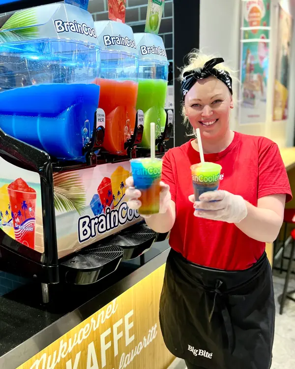 Dame fra Big Bite smiler mot kamera og holder slush