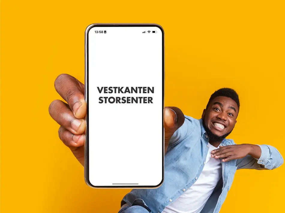 mann som smiler med telefon i hånden
