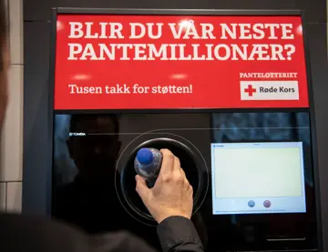 En hånd legger inn en flaske i en pantemaskin