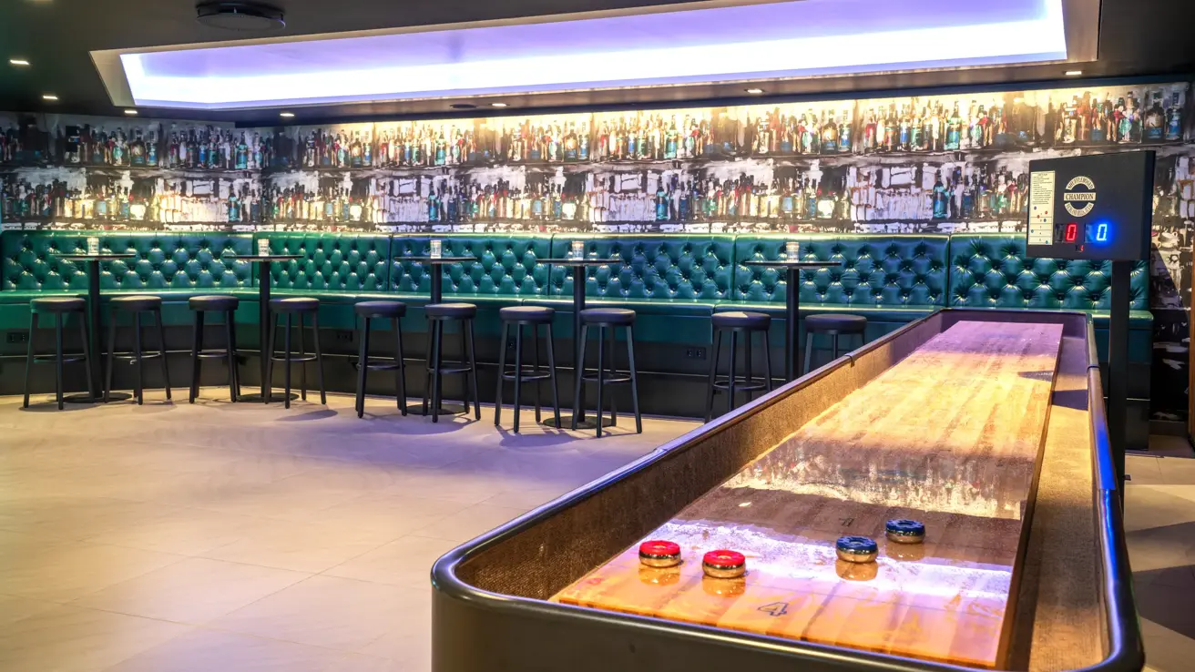shuffleboard, grønn skinnsofa, runde høye bord med barkrakker. 