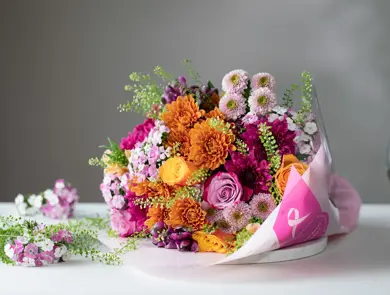 Flerfarget blomsterbukett ligger på et hvitt bord