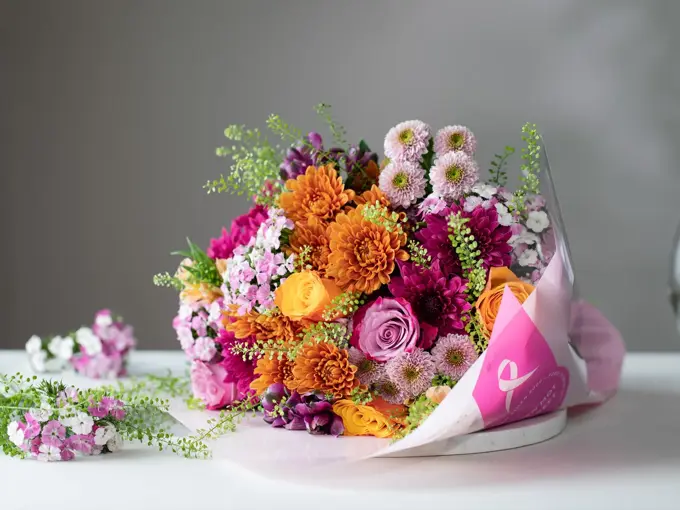 Flerfarget blomsterbukett ligger på et hvitt bord