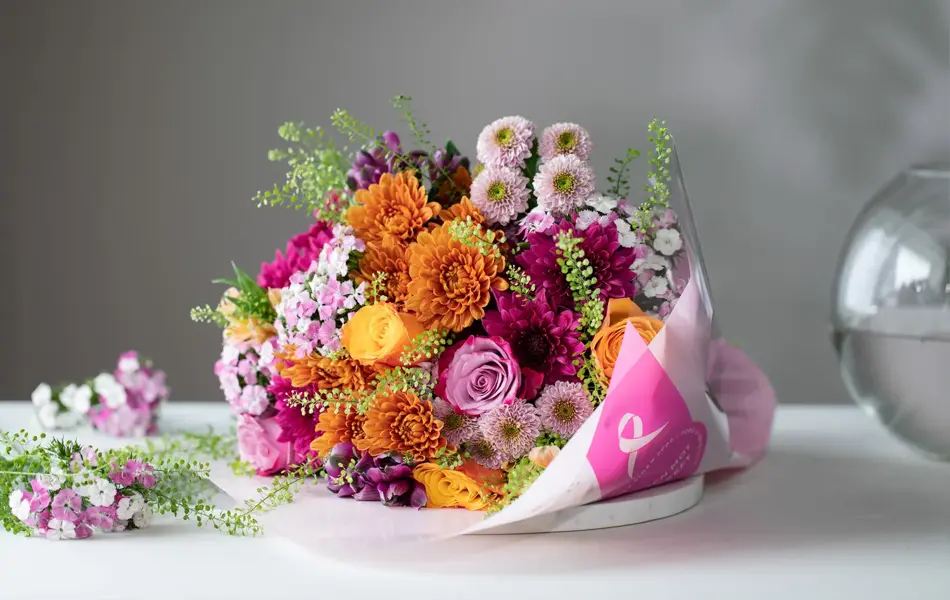 Flerfarget blomsterbukett ligger på et hvitt bord