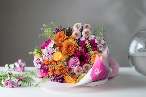 Flerfarget blomsterbukett ligger på et hvitt bord