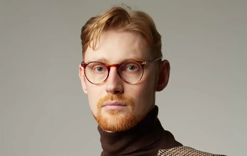 portrett av mann med briller, brun turtleneck genser og rutete høst kåpe