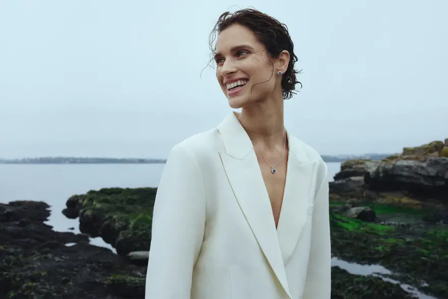 Dame i dressjakke som står ved et vann