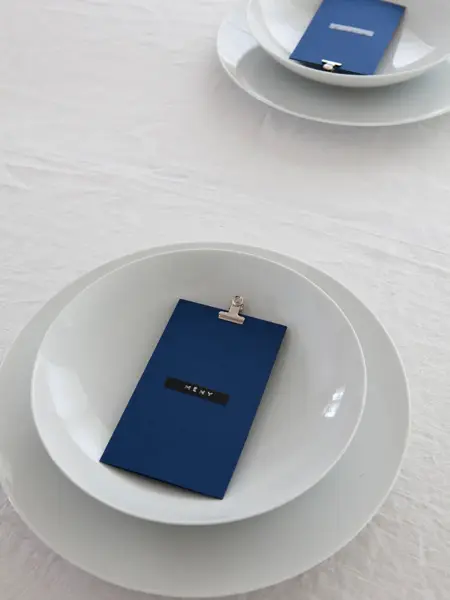 Steg 2 - Bord dekket med fire tallerkener og blått menykort