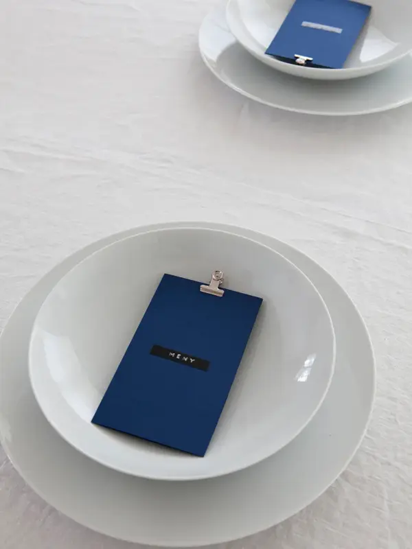 Steg 2 - Bord dekket med fire tallerkener og blått menykort