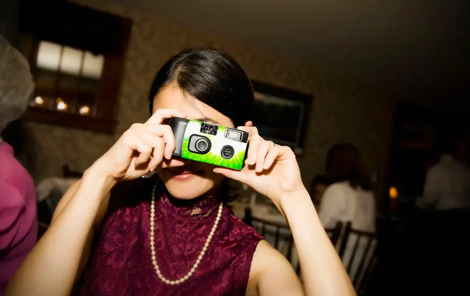 Festkledd, ung dame tar bilde med engangskamera.