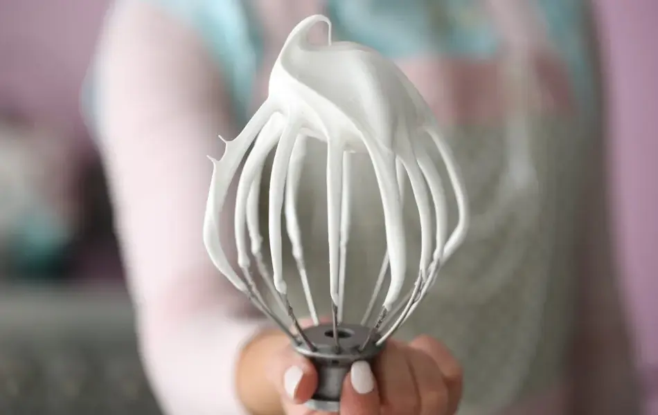 Hånd som holder en hjulvisp med marengsrester