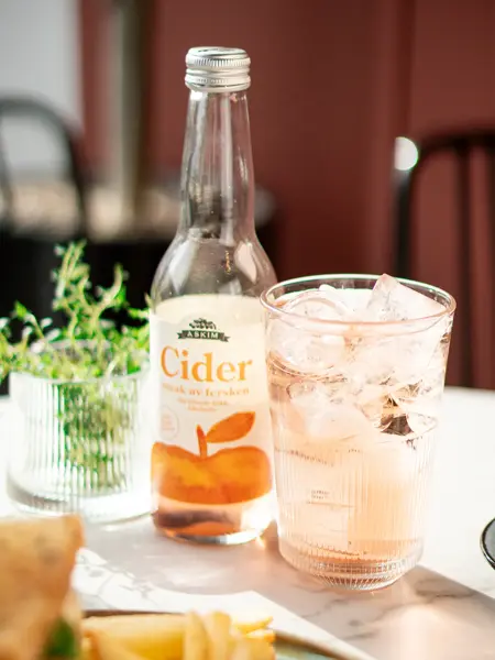 Flaske med Cider og glass med isbiter og drikke