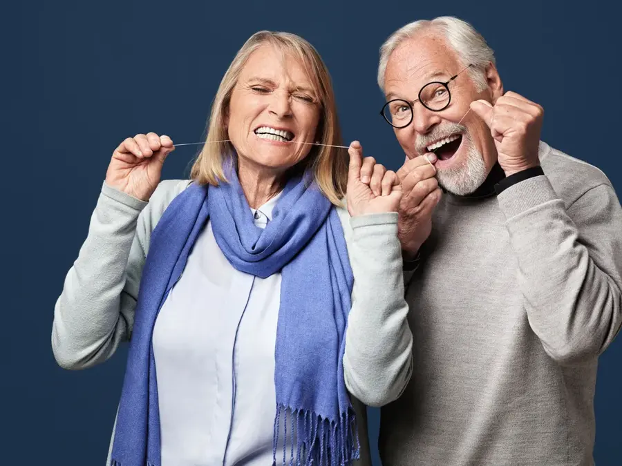 Mann og kvinne som bruker tanntråd