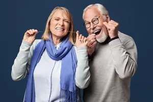 Mann og kvinne som bruker tanntråd