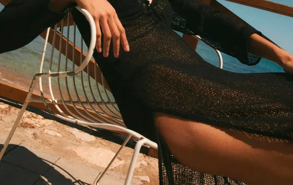 Modell ligger ute i en stol med sort bikini og sort heklet lang kjole.