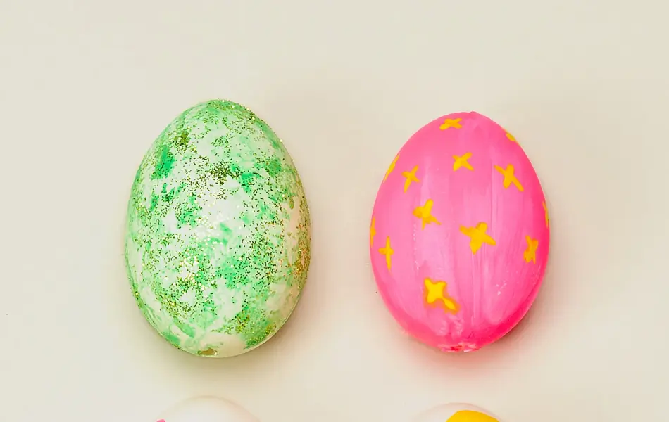 Fire egg dekorert med grønn, rosa og gul maling